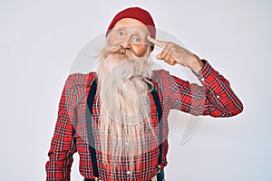 Old senior man with grey hair and long beard wearing hipster look with wool cap smiling pointing to head with one finger, great