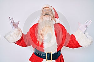Old senior man with grey hair and long beard wearing santa claus costume crazy and mad shouting and yelling with aggressive