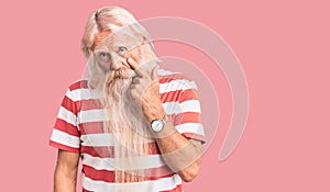 Old senior man with grey hair and long beard wearing striped tshirt pointing to the eye watching you gesture, suspicious