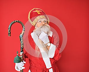 Old senior man with grey hair and long beard wearing traditional saint nicholas costume touching painful neck, sore throat for