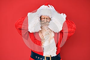 Old senior man with grey hair and long beard wearing traditional santa claus costume suffering from headache desperate and