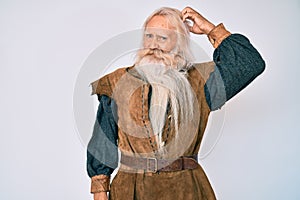Old senior man with grey hair and long beard wearing viking traditional costume confuse and wondering about question