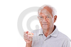 Old senior man with hand holding denture