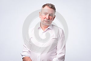 Old senior man in white shirt with serious and sad expression