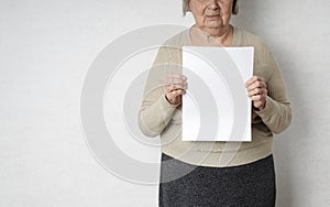 Old senior woman with empty white blank in her hands for copy space