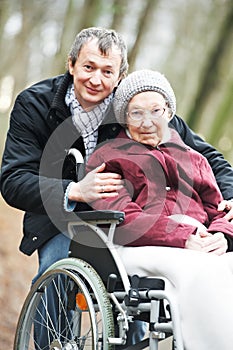 Old senior woman in wheelchair with careful son photo