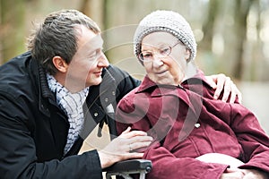 Old senior woman in wheelchair with careful son