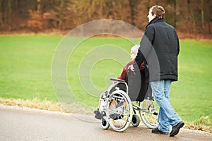 Old senior woman in wheelchair with careful son