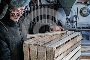 Old serious master in grey warm clothes and hat, in eyeglasses