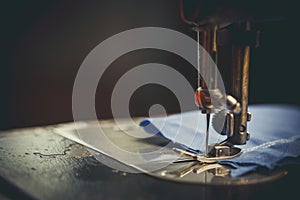 Old sewing machine, the man who sews on it, in dark colors