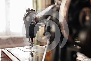 Old sewing machine stands on the table at home ready to work and sew.