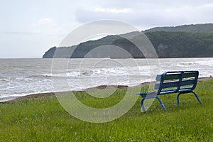 Old shabby blue bench on the shore of Japanese sea on a summer dull day before rain. No people