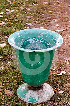 Old shabby green color trash can litter bin on the ground