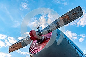 old aircraft engine propeller against the blue sky and clouds