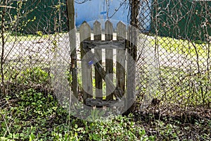 old shabby wooden wicket in chain-link fence