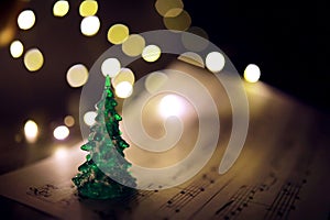 Old sheet with Christmas music notes as background against blurred lights. Christmas music concept