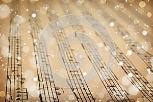 Old sheet with Christmas music notes as background, snowflakes and bokeh effect