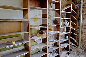 Old shelves for papers in an abandoned room. Rubbish and papers scattered around the room