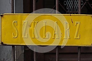 Old shiny golden plate on the door to a workshop of glazier in Poland Polish word `Szklarz` means glazier or glassmaker in Englis