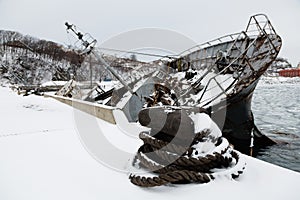 Old ship in disrepair sank at the pier in winter