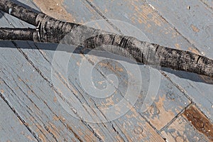 Old ship rope, wrapped splice joint, against a weathered wood and grey paint boat deck