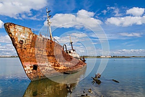 Old ship run aground and rusting in the shore photo