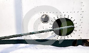 Old ship side with hole and hawser