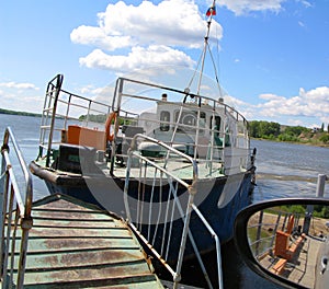 Old ship tractor pushing the ferry, old rusty bridge to enter the barge