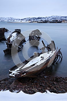 Old ships graveyard at the Barents sea rocky shore.