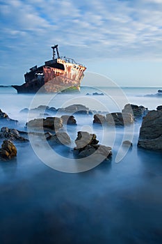 Old shipwreck long exposure on rocks at sunset