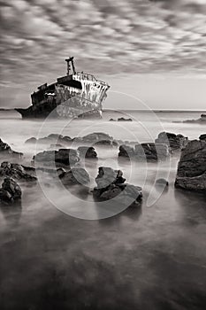 Old shipwreck long exposure on rocks at sunset artistic conversion