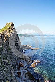 An old shipwrecked ship stands on the shore at the foot of a rocky cliff. Cape Briner. Primorsky Krai. Russia