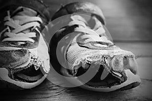 Old shoes with holes shoelaces worn shabby homeless clothing