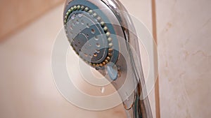 Old shower head with falling stream of water drops dripping into bathroom