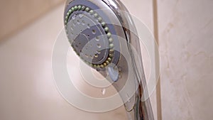 Old Shower head with Falling Stream of Water Drops Dripping into Bathroom