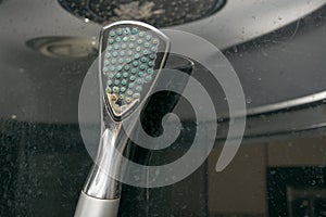 Old shower head, nozzles clogged with limestone and covered with dirty stains, shower walls in dirty stains in the bathroom