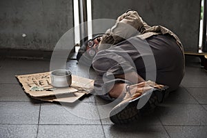 Old sick beggar or Homeless dirty man sleep on footpath with donate bowl, dollar bill, coin, paper cardboard with help text.