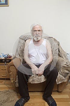 Old sick lonely man in the armchair at home