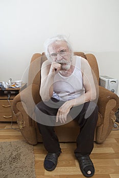 Old sick lonely man in the armchair at home