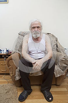 Old sick lonely man in the armchair at home