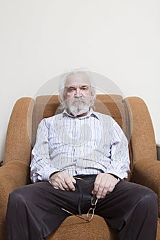 Old sick lonely man in the armchair at home