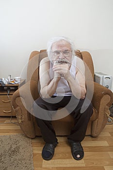 Old sick lonely man in the armchair at home