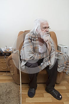 Old sick lonely man in the armchair at home