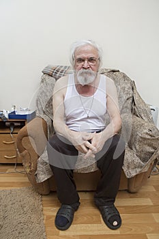 Old sick lonely man in the armchair at home