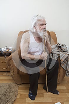 Old sick lonely man in the armchair at home