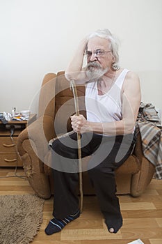 Old sick lonely man in the armchair at home