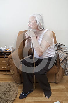 Old sick lonely man in the armchair at home