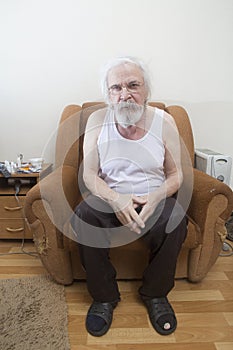 Old sick lonely man in the armchair at home