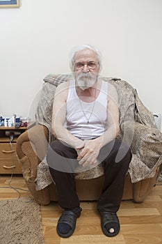 Old sick lonely man in the armchair at home