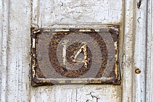 Old sign with the house number 14 on the background of the wall.